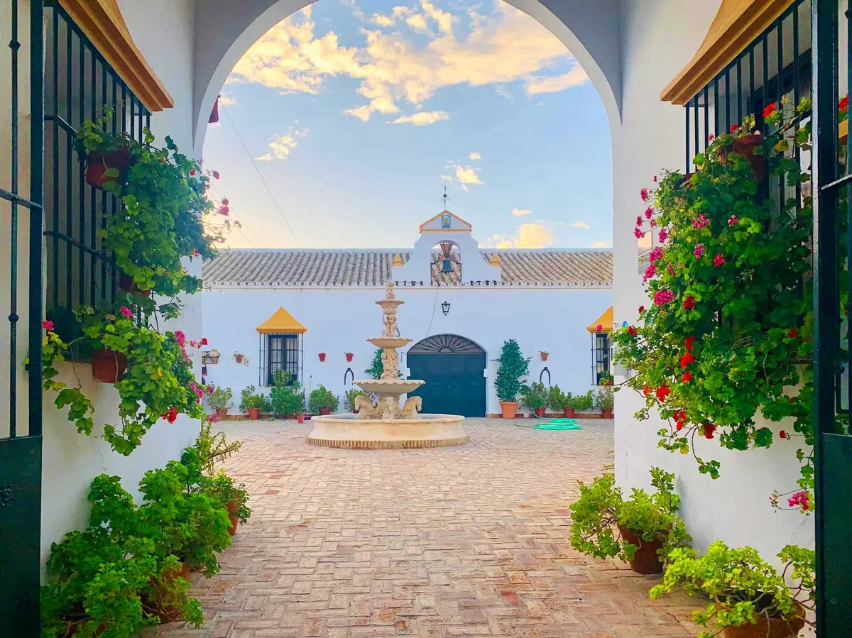 patio fuente entrada arco geranios atardecer